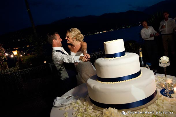   Caroline and Tony's wedding - July 2012 Cutting of the big wedding cake! A blue themed wedding for Caroline and Tony. At night with the lake as backdrop - photo by Independent Pictures.